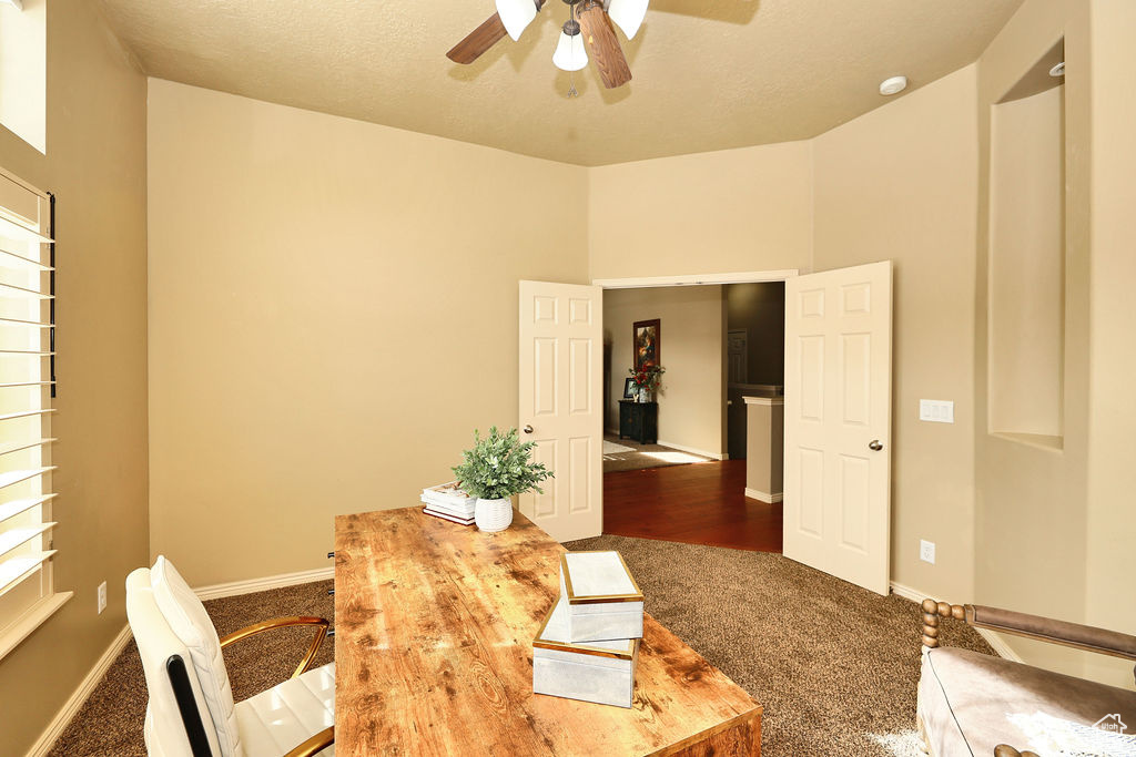 Office space with ceiling fan, dark colored carpet, a textured ceiling, and baseboards