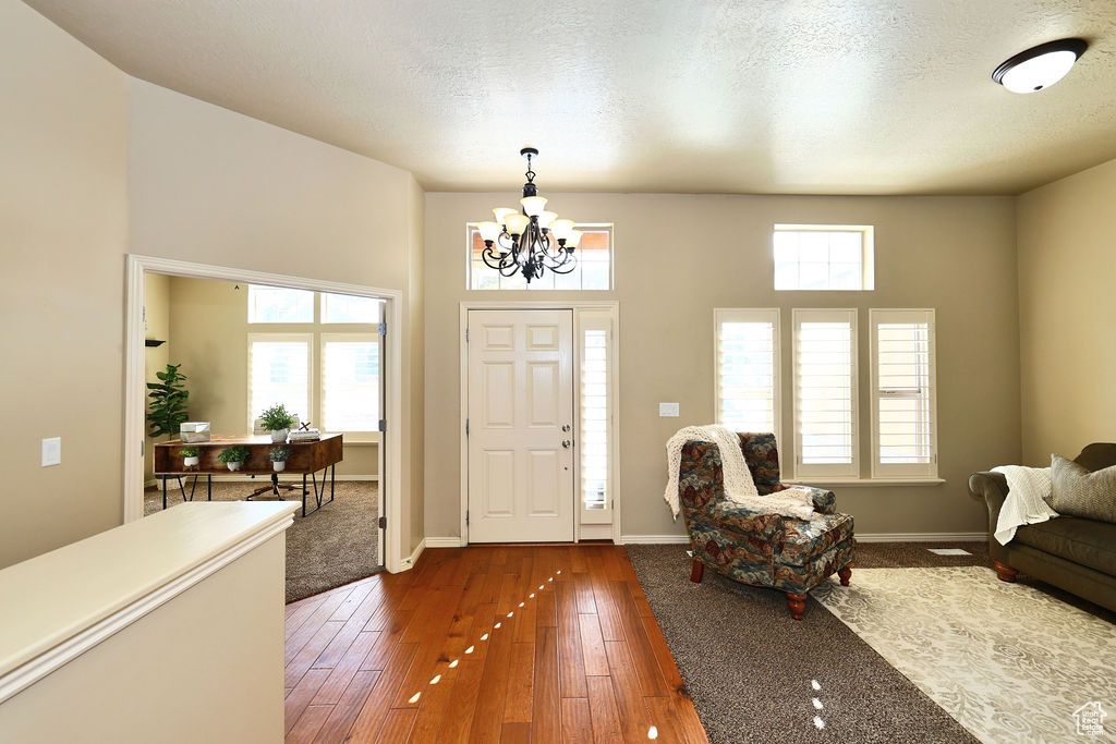 Entryway featuring dark wood-type flooring, a textured ceiling, baseboards, and an inviting chandelier