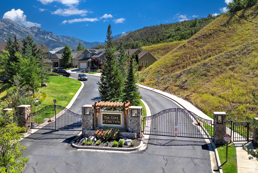 View of street featuring a gate, a gated entry, a mountain view, and curbs