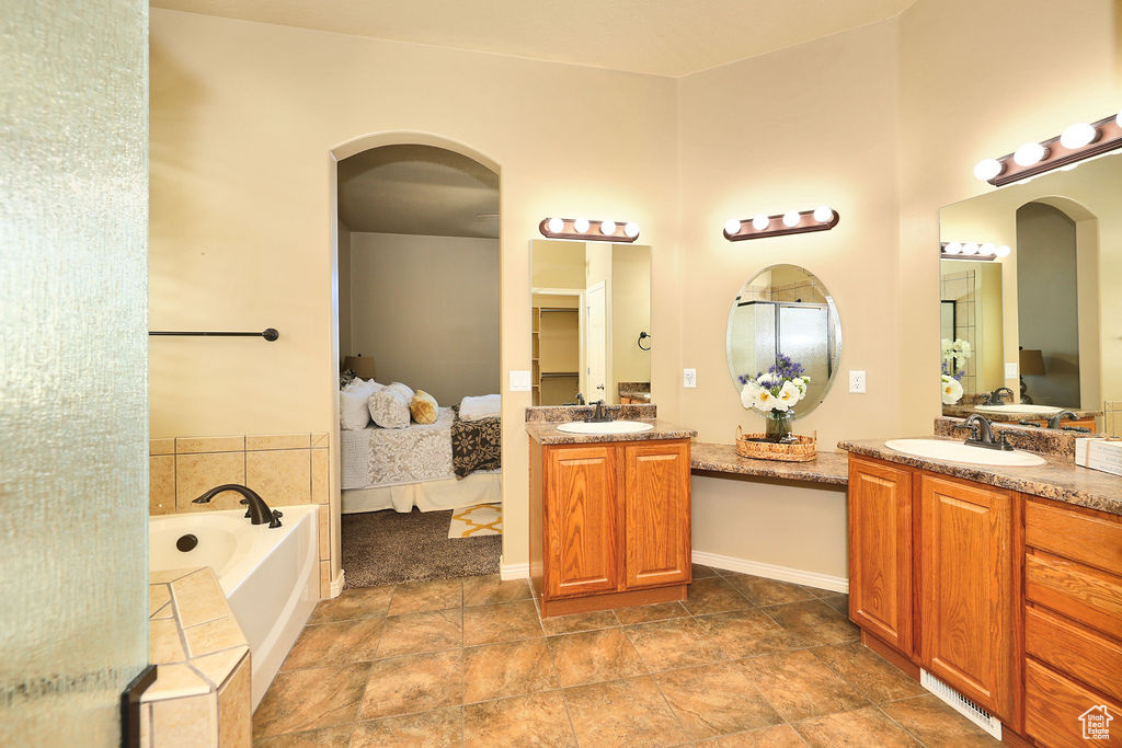 Ensuite bathroom featuring a bath, ensuite bath, two vanities, and a sink
