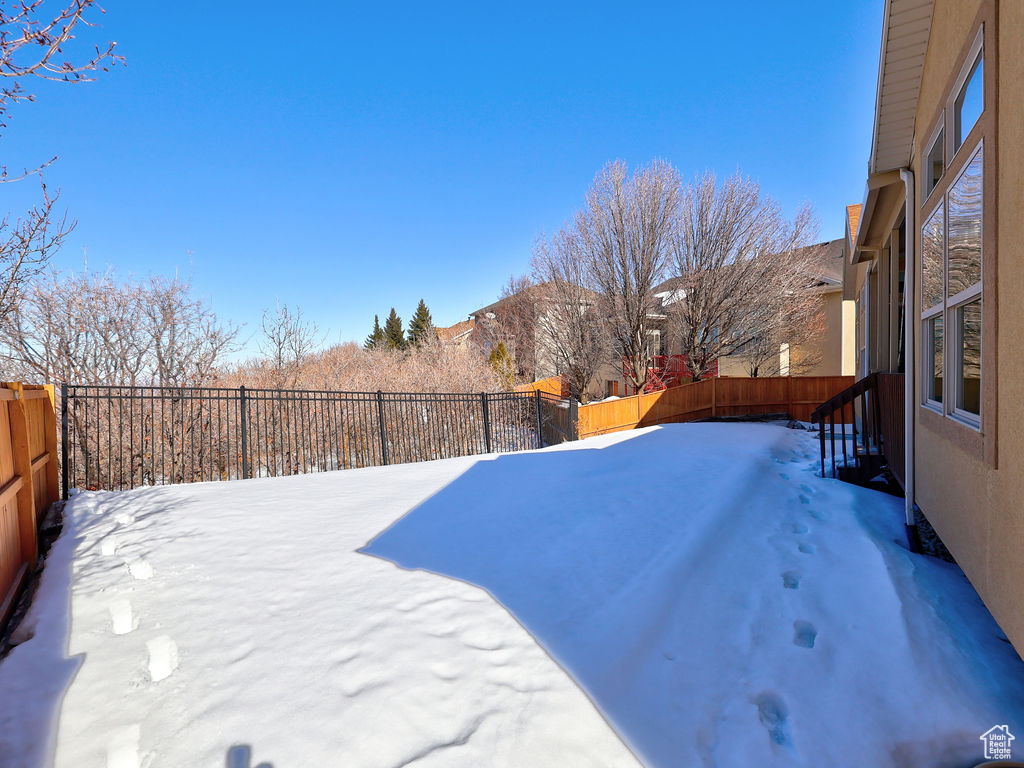 Yard covered in snow featuring a fenced backyard