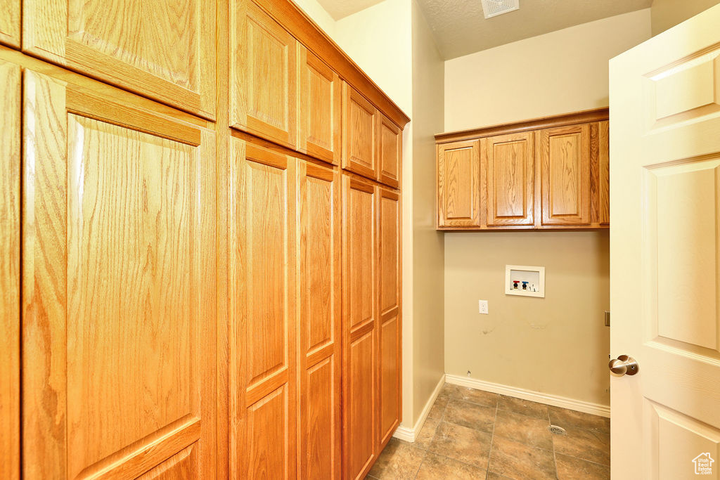 Washroom featuring washer hookup, cabinet space, and baseboards
