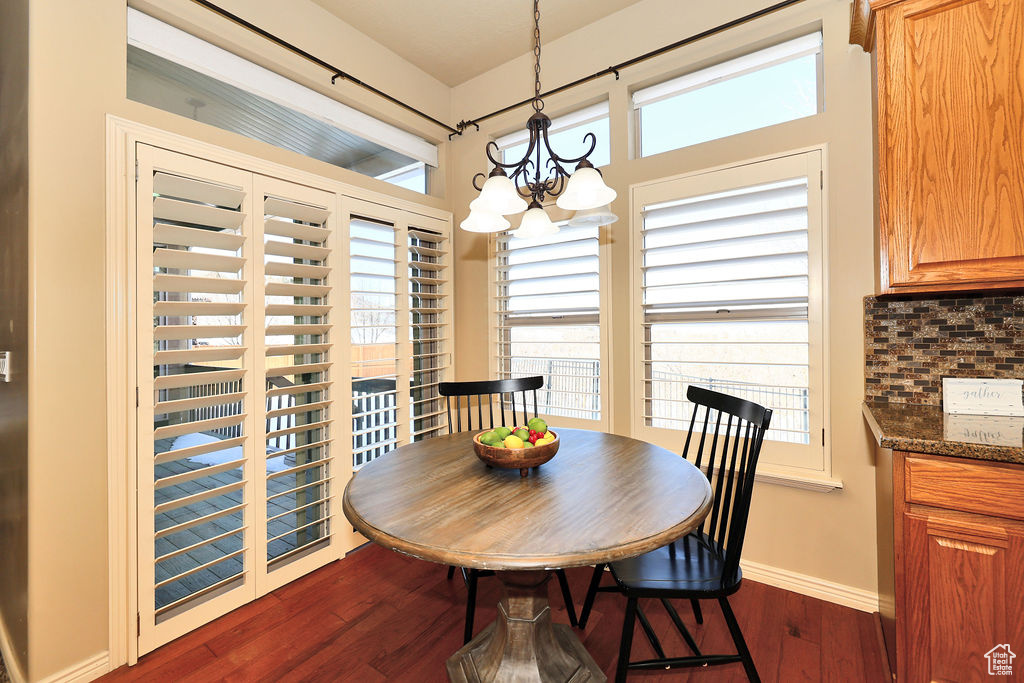 Dining room featuring a notable chandelier, dark wood finished floors, and a healthy amount of sunlight
