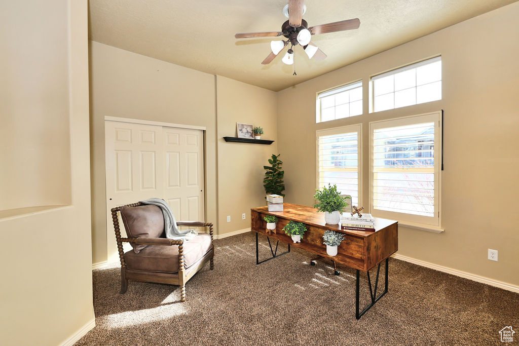 Office space with dark colored carpet, ceiling fan, and baseboards