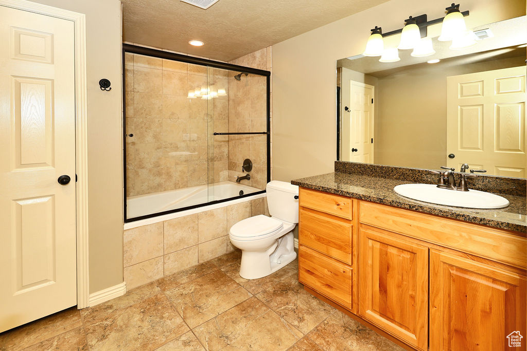 Full bathroom featuring visible vents, toilet, tiled shower / bath combo, a textured ceiling, and vanity