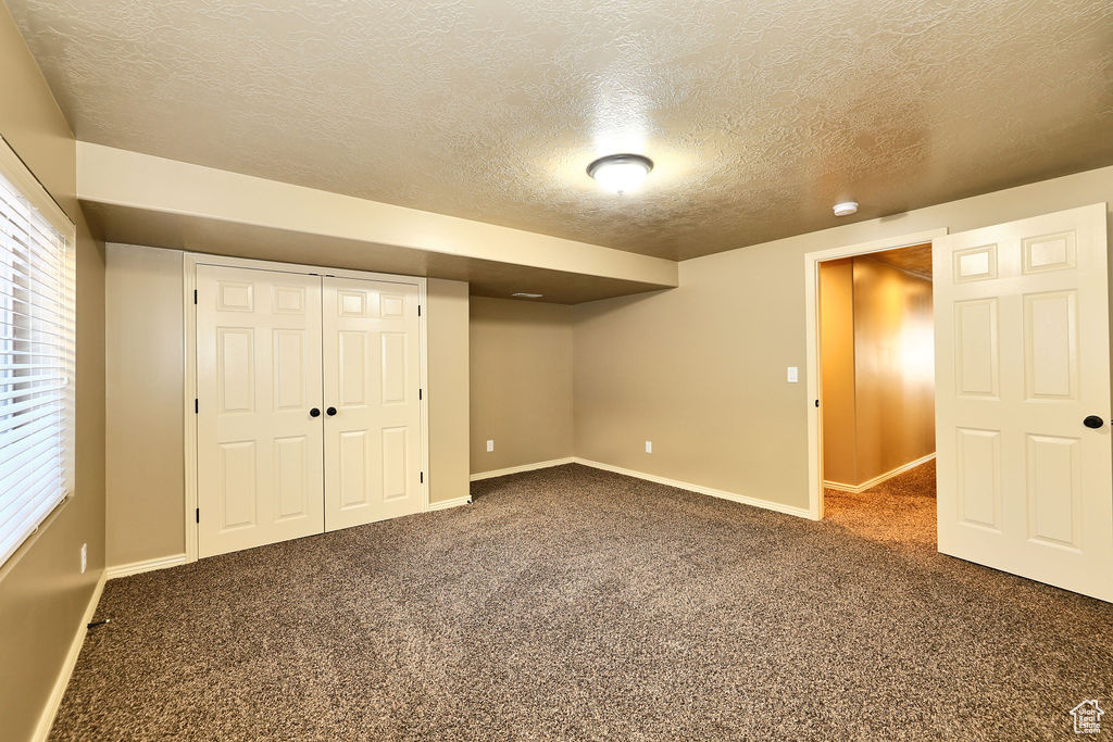 Basement featuring carpet, a healthy amount of sunlight, a textured ceiling, and baseboards