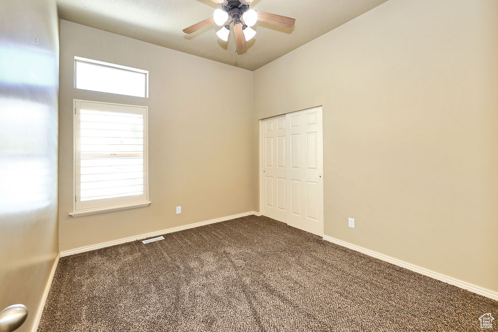 Unfurnished bedroom with a closet, multiple windows, dark carpet, and baseboards