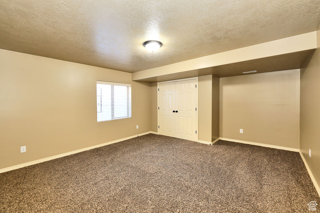 Interior space featuring carpet floors, baseboards, and a textured ceiling