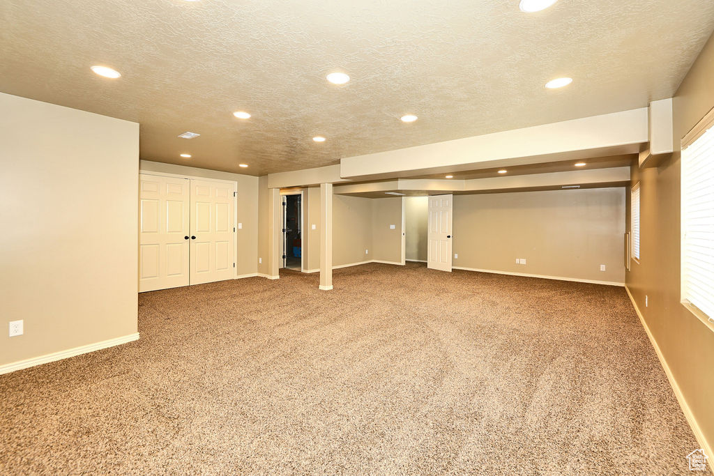 Basement with a textured ceiling, recessed lighting, carpet, and baseboards