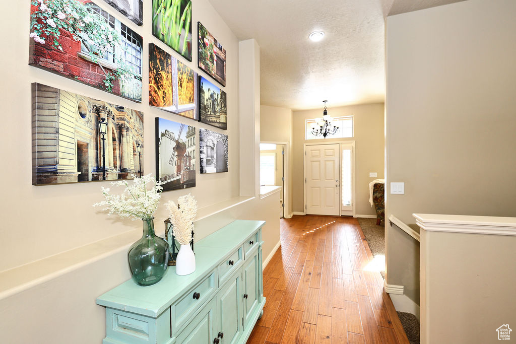 Foyer entrance with a chandelier, a textured ceiling, wood finished floors, and baseboards
