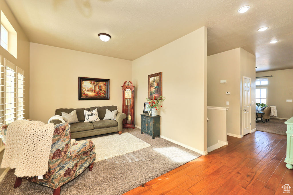 Living room featuring recessed lighting, a textured ceiling, baseboards, and wood finished floors