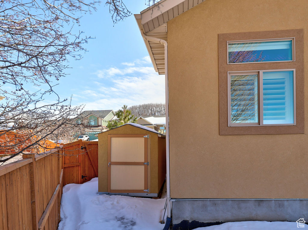 Exterior space with an outbuilding, a storage unit, and stucco siding