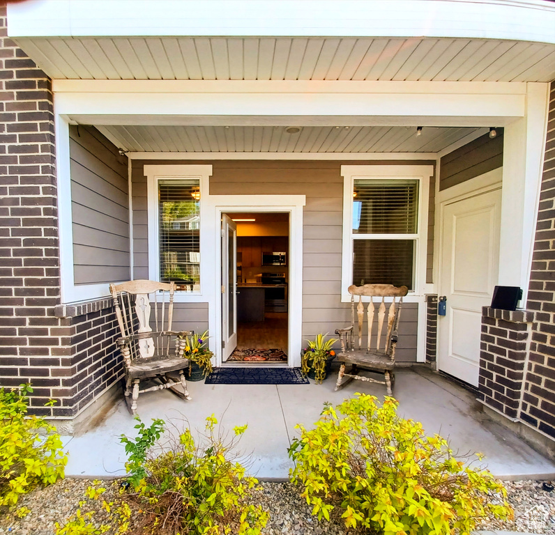 Entrance to property featuring covered porch and brick siding