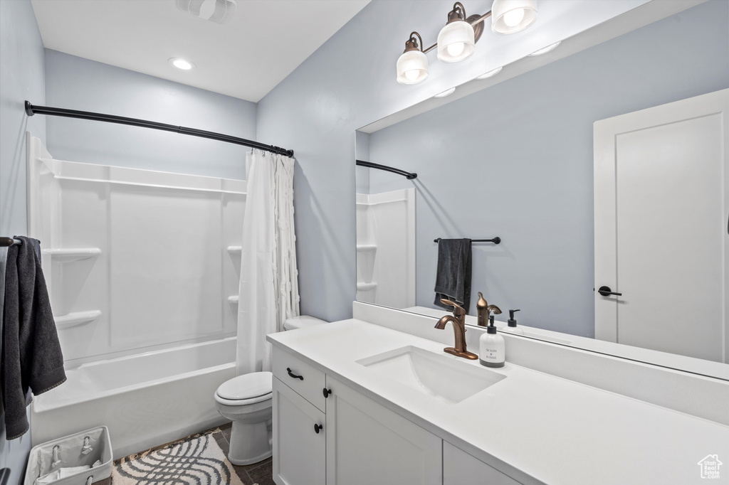 Bathroom with toilet, shower / tub combo, and vanity
