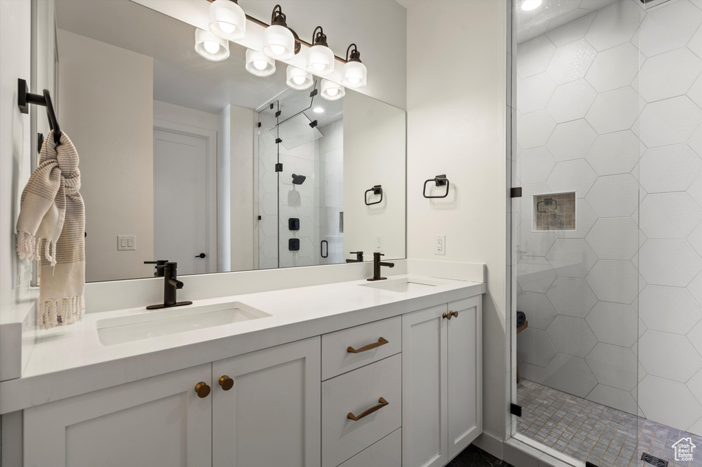 Bathroom featuring a sink, a shower stall, and double vanity