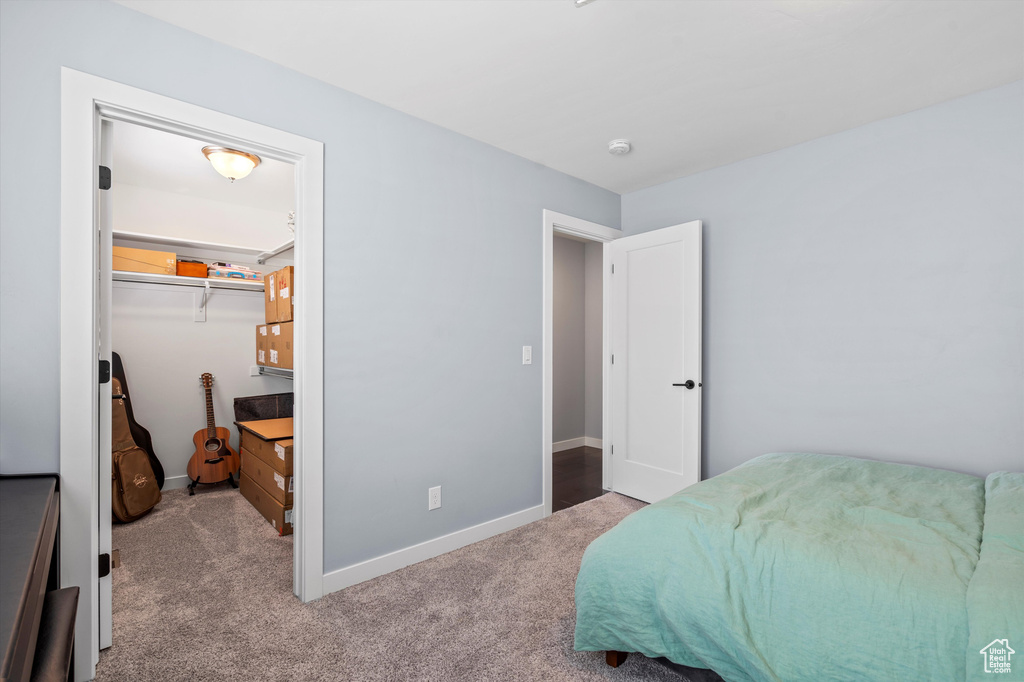 Bedroom featuring light carpet, a spacious closet, baseboards, and a closet