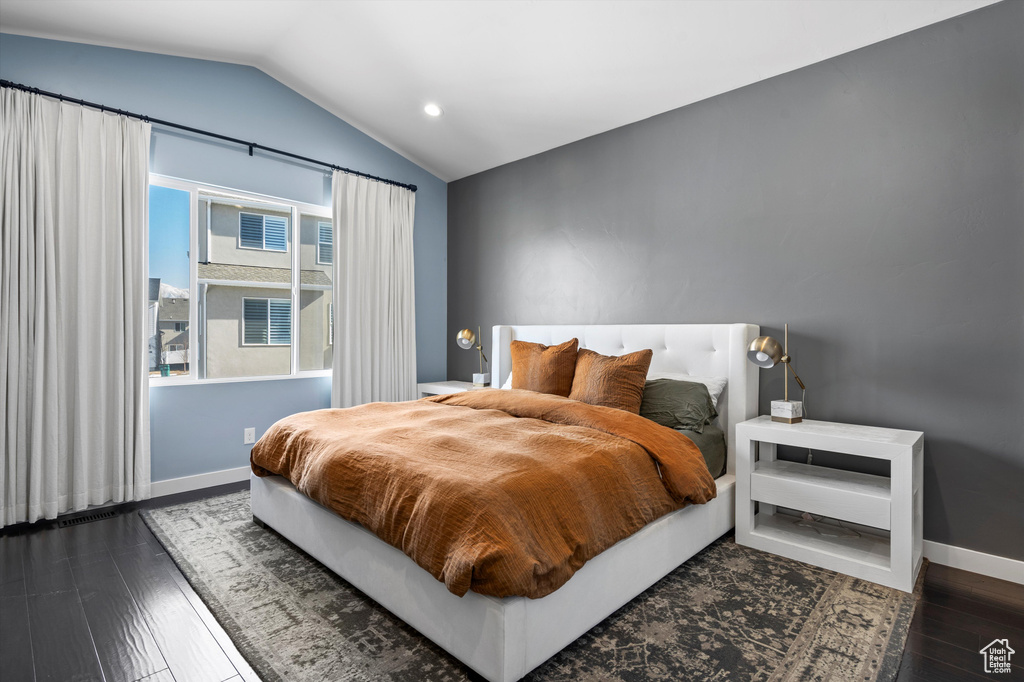 Bedroom featuring dark wood-type flooring, lofted ceiling, and baseboards