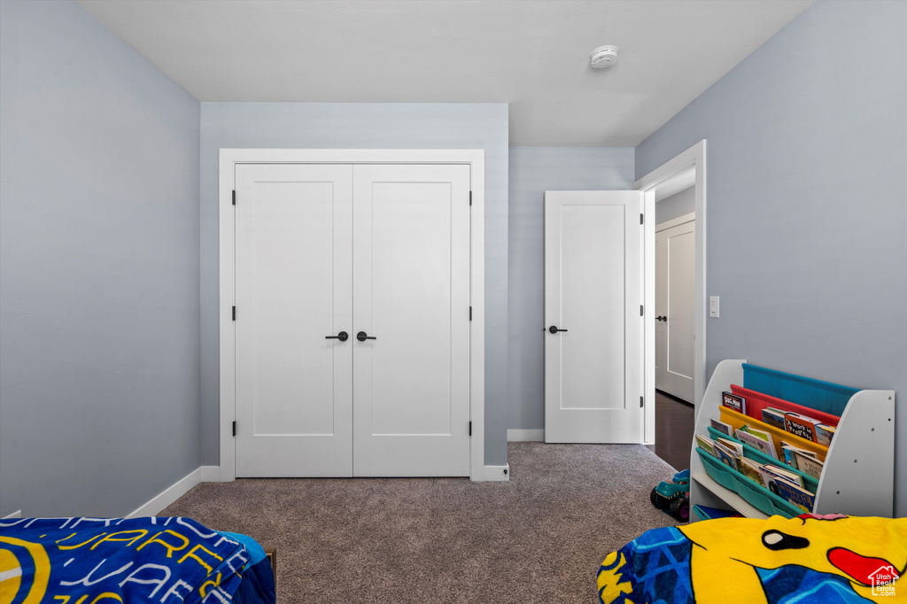 Bedroom with a closet, dark carpet, and baseboards