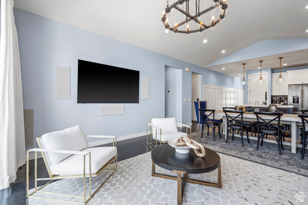 Living room featuring lofted ceiling, a chandelier, recessed lighting, wood finished floors, and baseboards