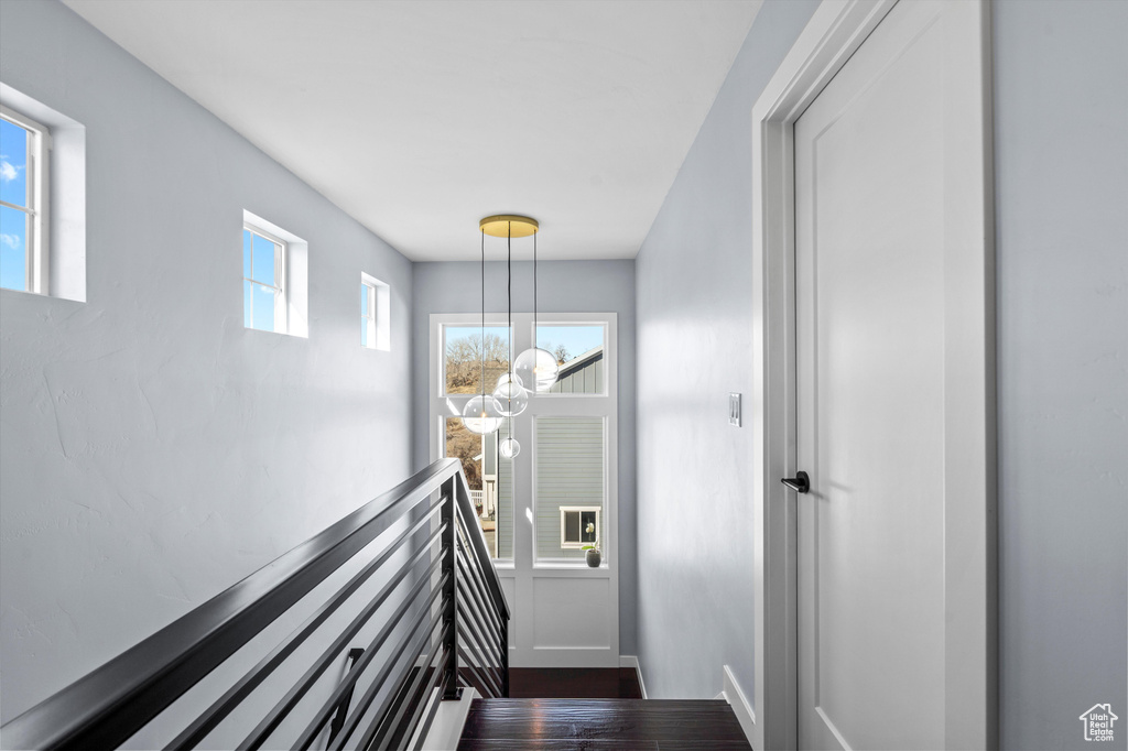 Interior space with baseboards, a notable chandelier, and wood finished floors