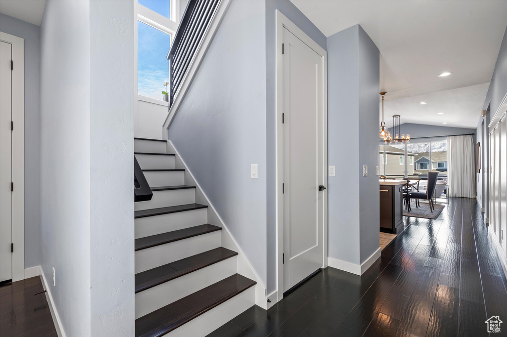 Stairs featuring baseboards, vaulted ceiling, a wealth of natural light, and wood finished floors