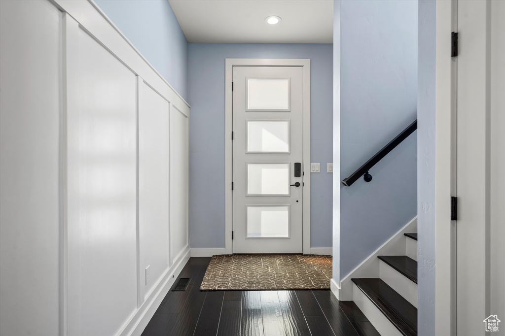 Entrance foyer featuring dark wood-style floors, visible vents, stairway, and baseboards