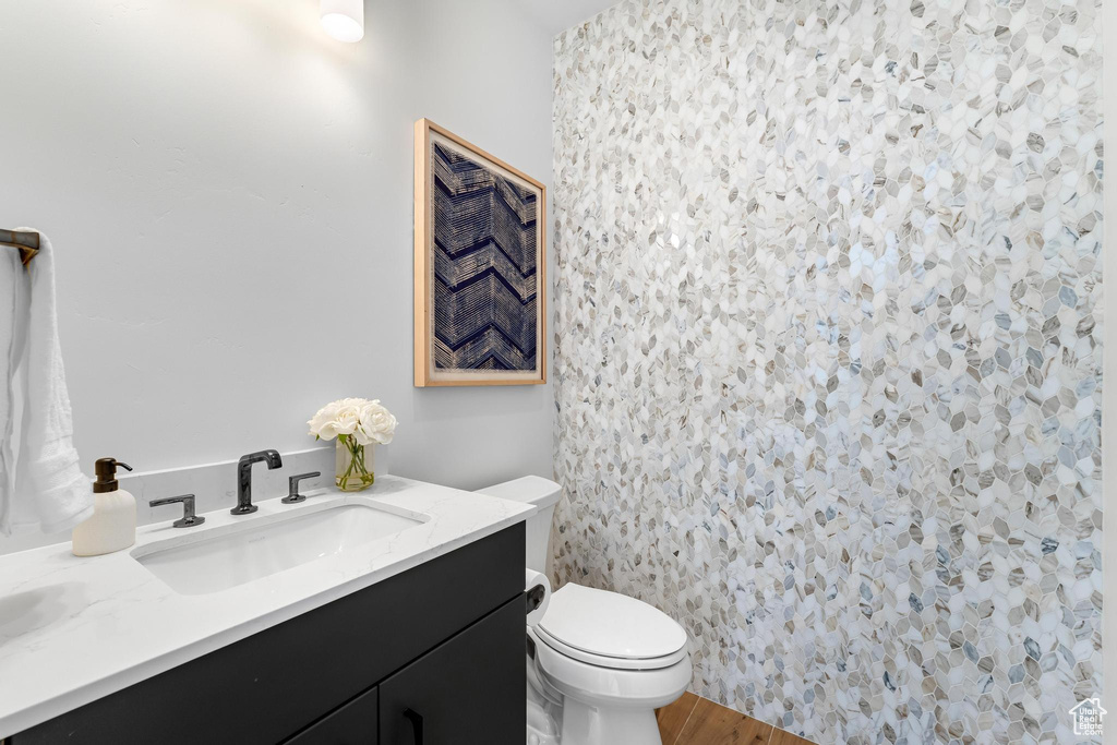 Bathroom featuring toilet, wood finished floors, and vanity