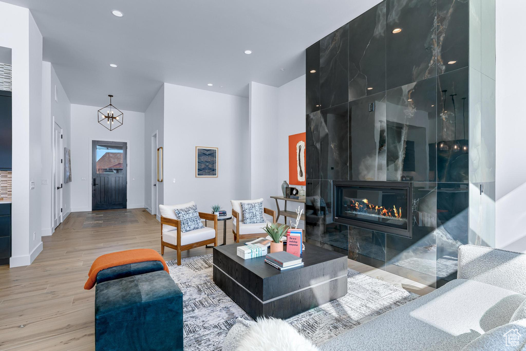 Living room with a chandelier, recessed lighting, a fireplace, and wood finished floors