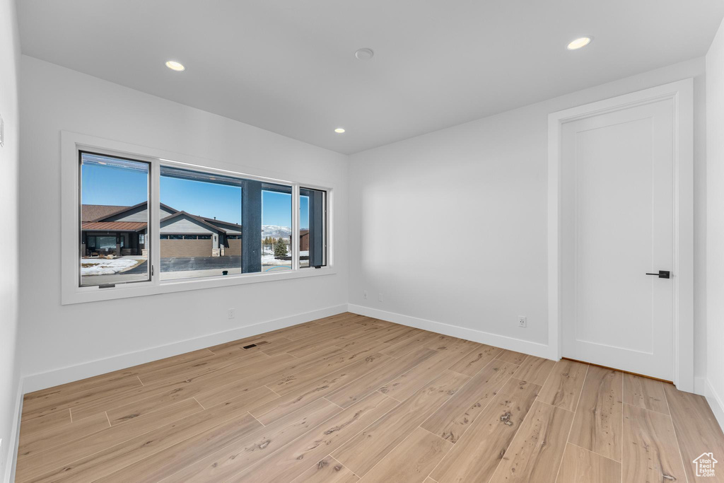 Empty room with light wood finished floors, visible vents, baseboards, and recessed lighting