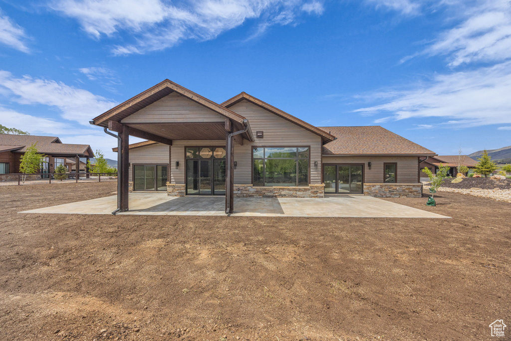 Rear view of property with a patio area and stone siding