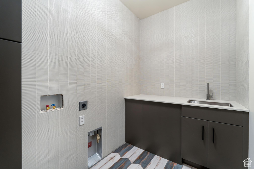 Laundry area featuring tile walls, cabinet space, a sink, and electric dryer hookup