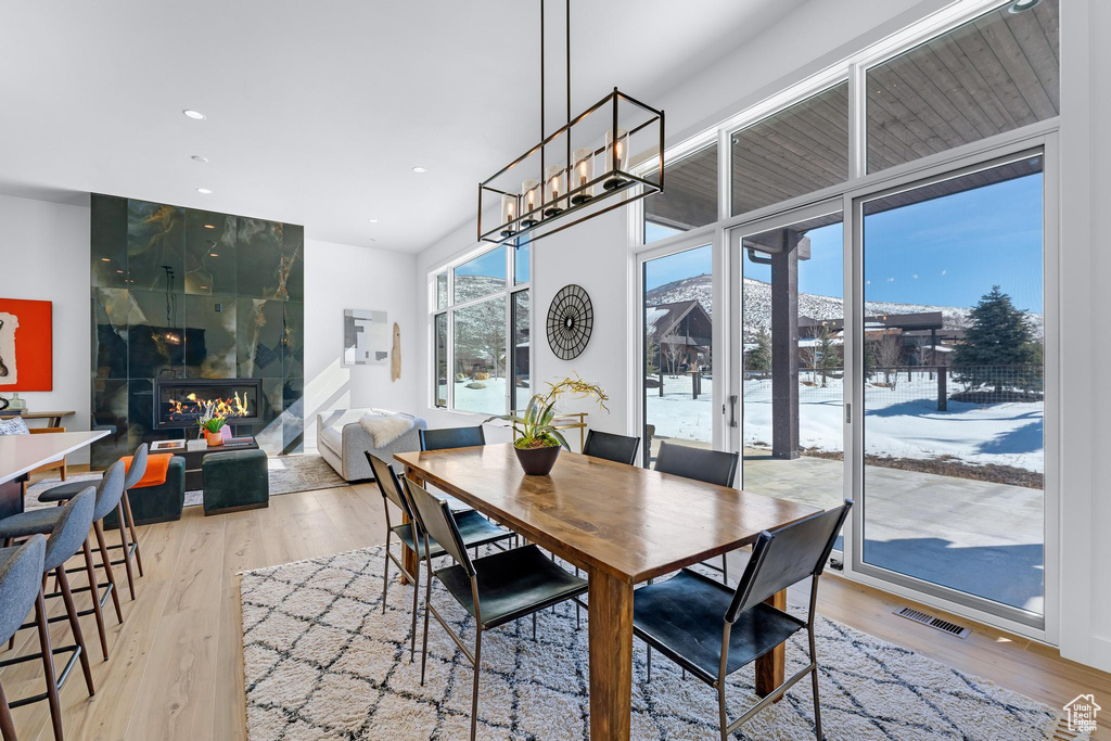 Dining area featuring light wood finished floors, recessed lighting, visible vents, and a tile fireplace