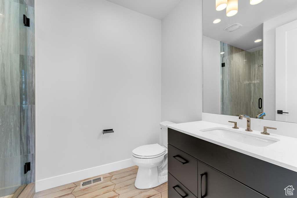 Bathroom featuring a stall shower, baseboards, visible vents, toilet, and vanity