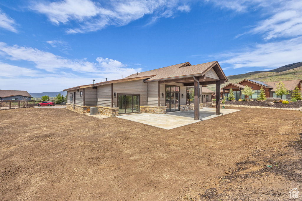 Back of house featuring a patio, stone siding, a mountain view, and central AC unit