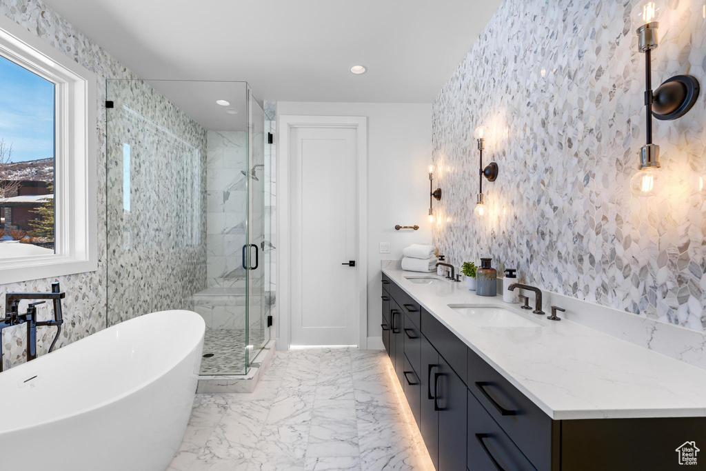 Full bath with a freestanding tub, a sink, marble finish floor, a shower stall, and double vanity