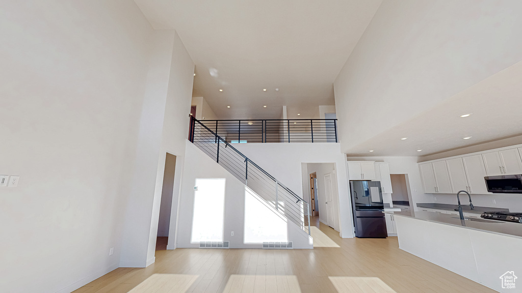 Kitchen featuring light wood-type flooring, stainless steel microwave, white cabinets, and freestanding refrigerator