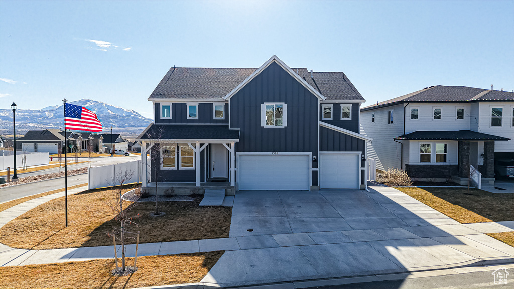 View of front of home featuring a mountain view, a garage, fence, concrete driveway, and board and batten siding