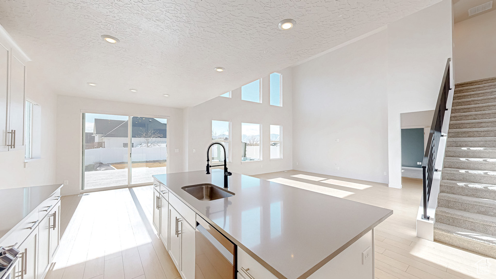 Kitchen with a kitchen island with sink, white cabinets, and a sink