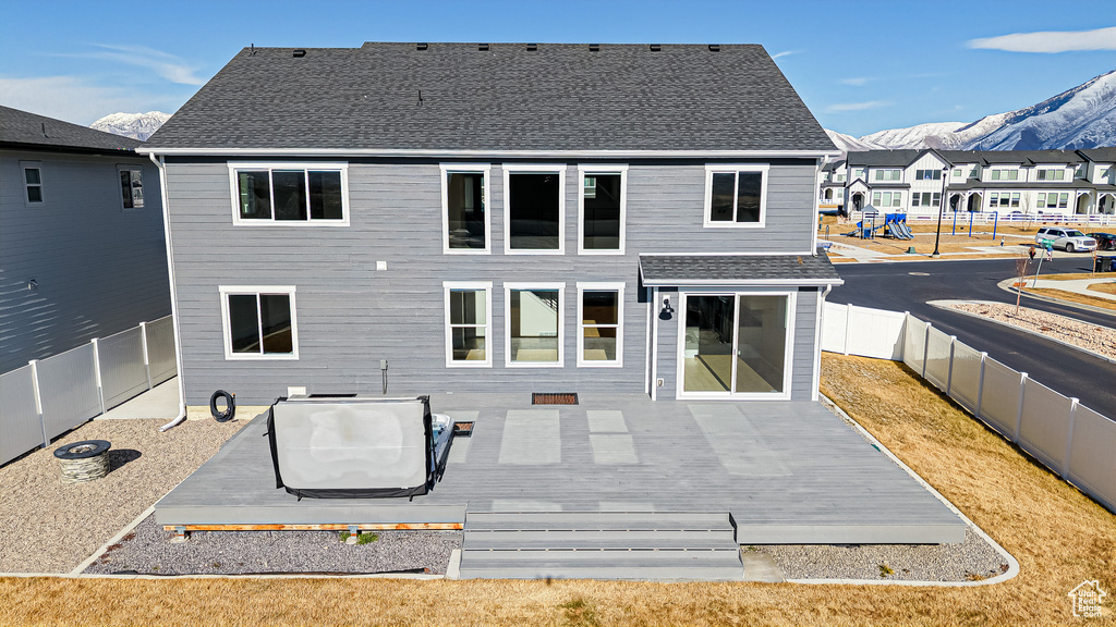 Rear view of property featuring a deck with mountain view, a fenced backyard, a residential view, and a shingled roof