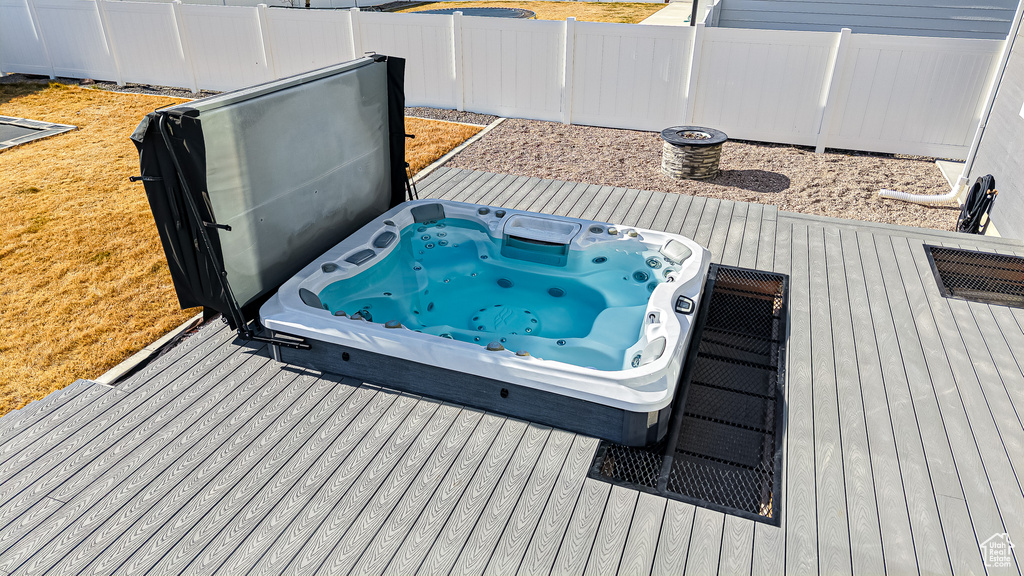 Wooden deck featuring a covered hot tub and fence