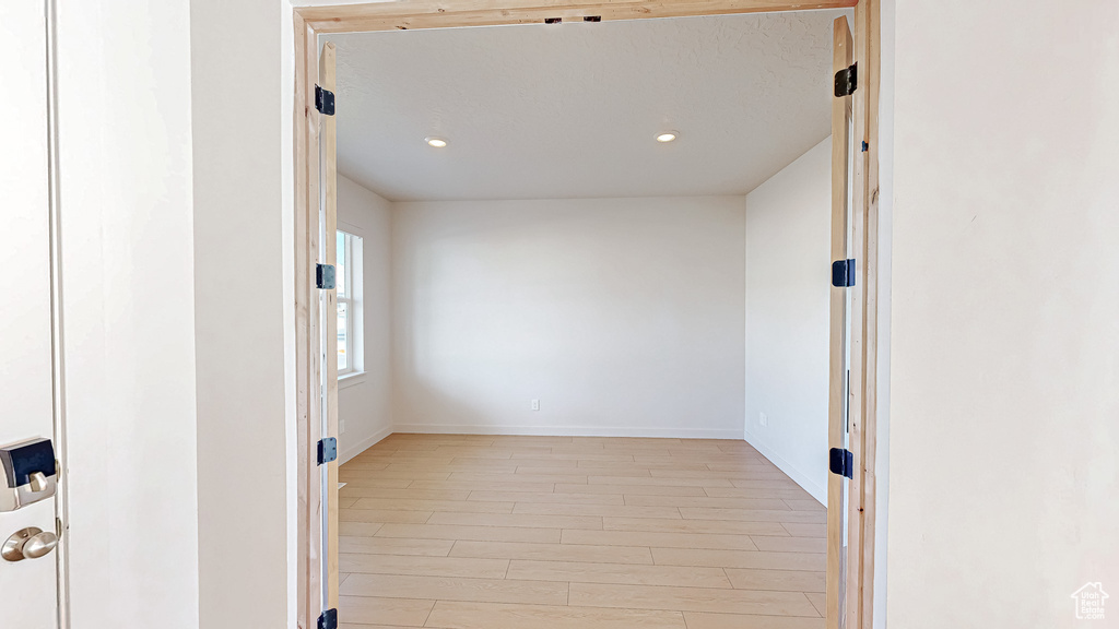 Unfurnished room with light wood finished floors, baseboards, and recessed lighting