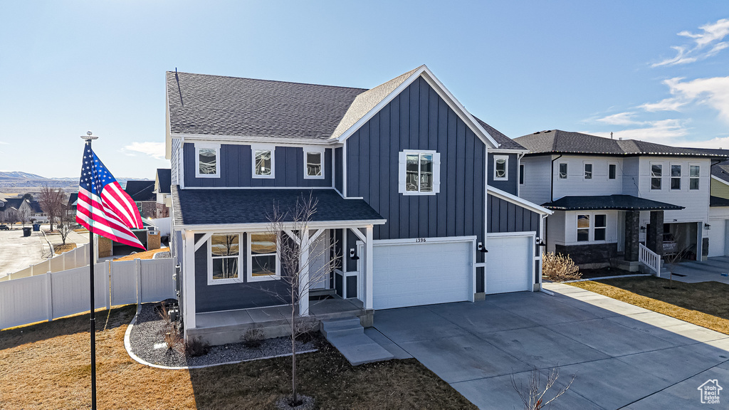 Modern farmhouse featuring board and batten siding, concrete driveway, fence, and a garage