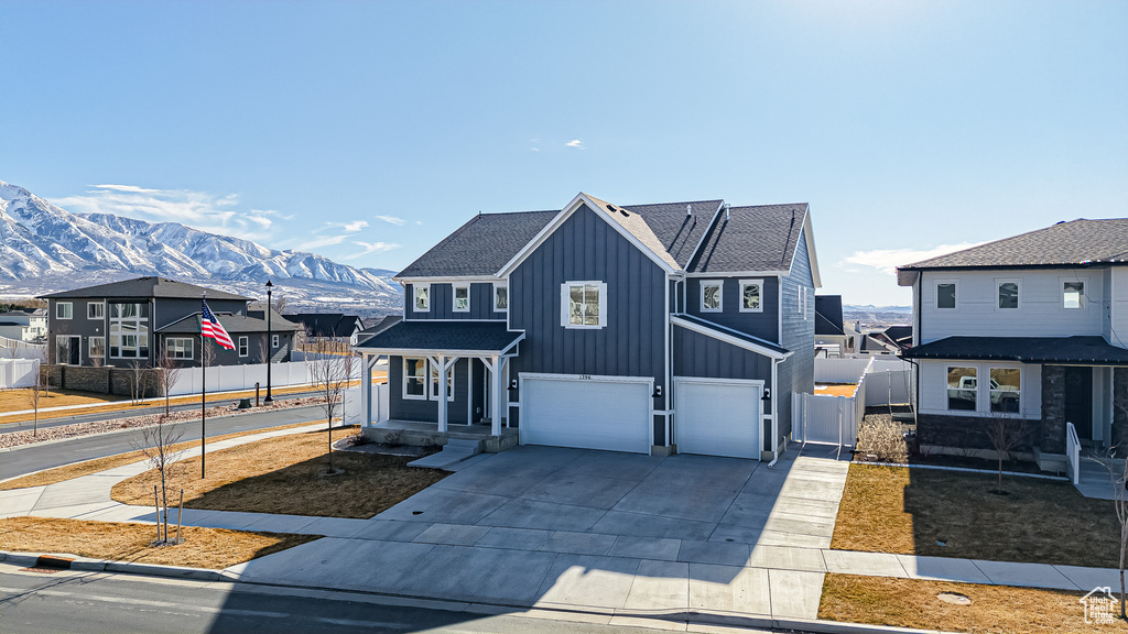 View of front of home with a mountain view, a garage, fence, concrete driveway, and board and batten siding