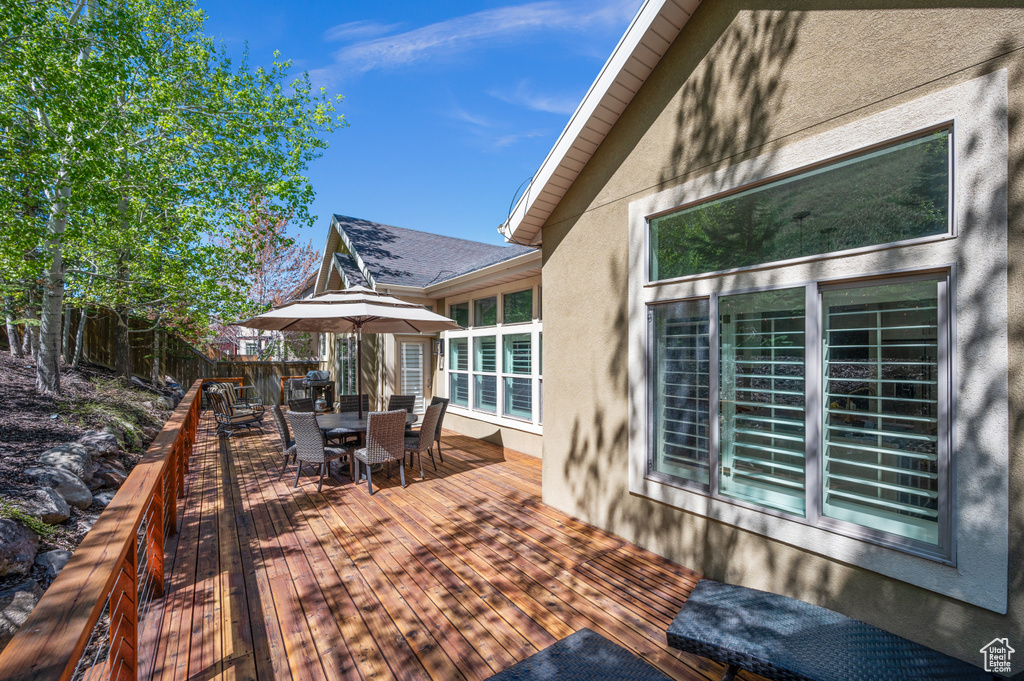 Wooden terrace with outdoor dining space and a fenced backyard
