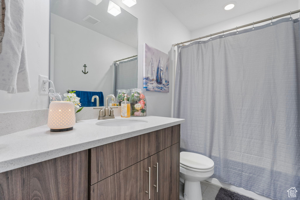 Bathroom with toilet, vanity, visible vents, tile patterned floors, and shower / bath combo