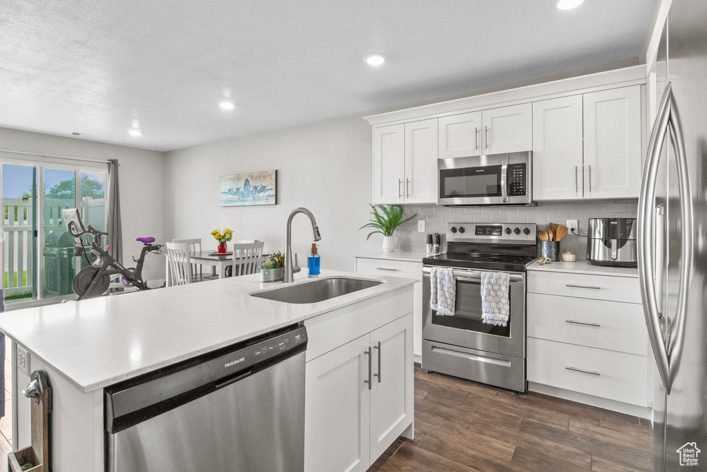Kitchen featuring appliances with stainless steel finishes, a sink, a center island with sink, light countertops, and recessed lighting