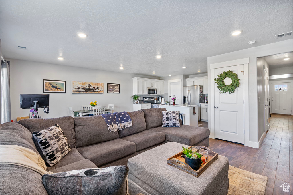 Living room with hardwood / wood-style flooring, visible vents, a textured ceiling, and recessed lighting