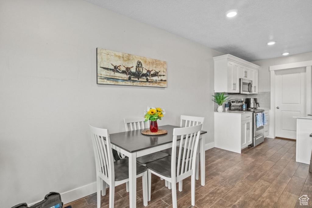Dining room with dark wood-type flooring, recessed lighting, and baseboards