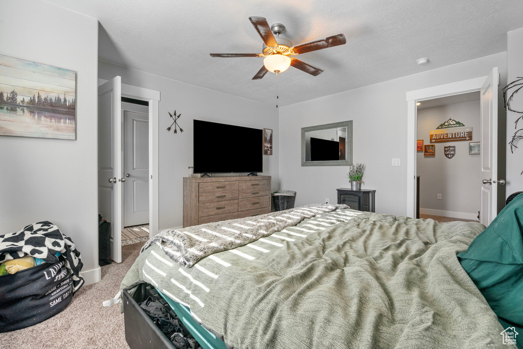 Bedroom featuring a textured ceiling, baseboards, a ceiling fan, and light colored carpet