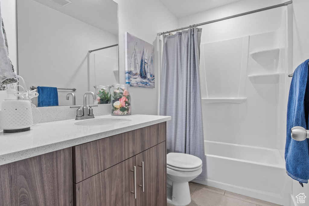 Full bathroom featuring tile patterned floors, toilet, vanity, and shower / bath combination with curtain